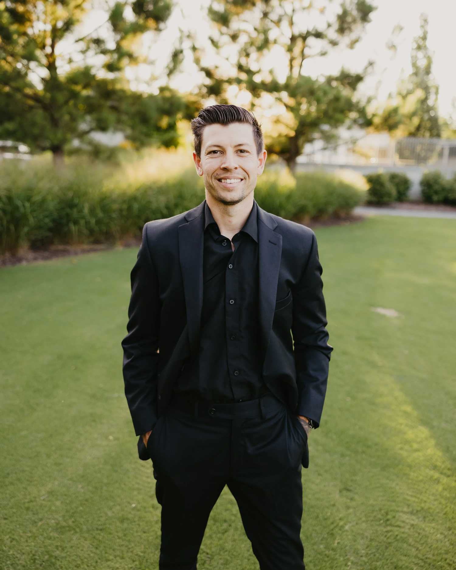 Trevor McDonald, founder and lead creative director of Reel Time Films, standing outdoors in a black suit